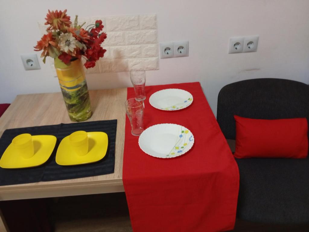 une table avec deux plaques et un tissu de table rouge dans l'établissement Апартамент в Новобудові Стрийська Автовокзал, à Lviv