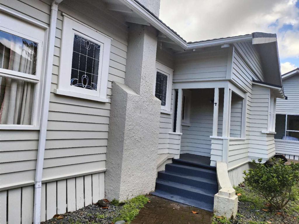 uma casa branca com um alpendre azul e escadas em Cozy 5 bedrooms house 7 Rangiatea Road, Epsom em Auckland