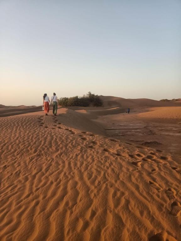 two people walking on the sand in the desert at dar Brahim in Mhamid