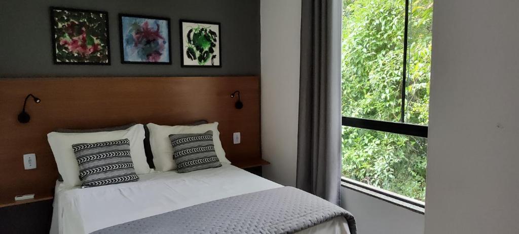 - une chambre avec un lit doté d'oreillers et d'une fenêtre dans l'établissement Flats das Palmeiras, à Florianópolis