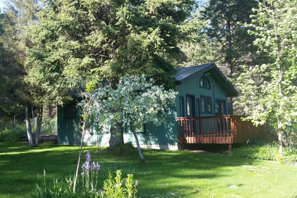 a green cabin in the middle of a yard at Cottage at Foys Lake Montana in Kalispell
