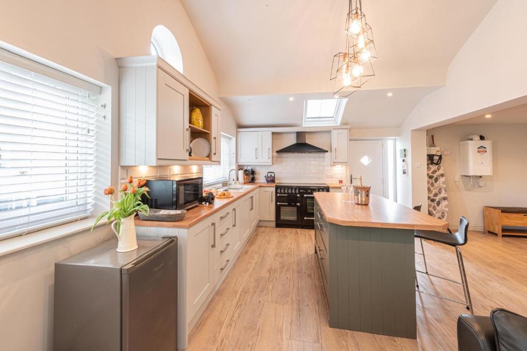 a kitchen with white cabinets and a wooden counter top at Quiet Self contained Cottage near Delamere Forest in Cuddington