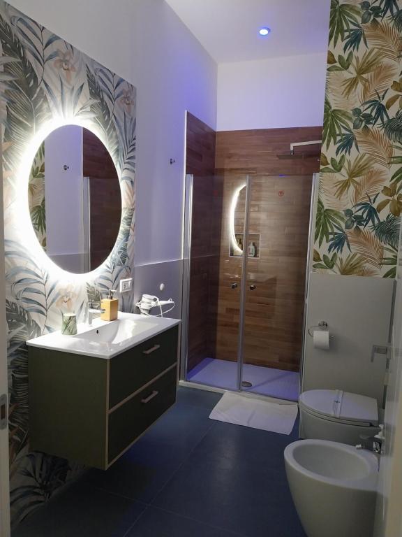 bagno con lavandino, servizi igienici e specchio di Suite al Borgo ad Aversa