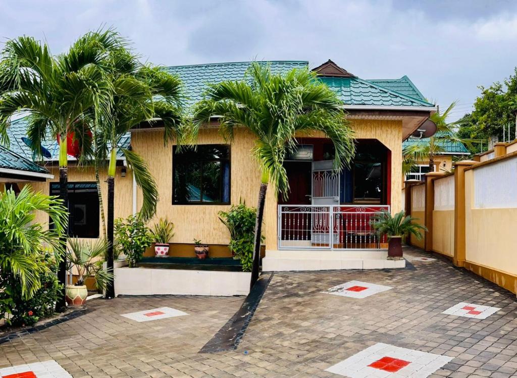 a house with two palm trees in front of it at Queen Elizabeth Apartment in Dar es Salaam
