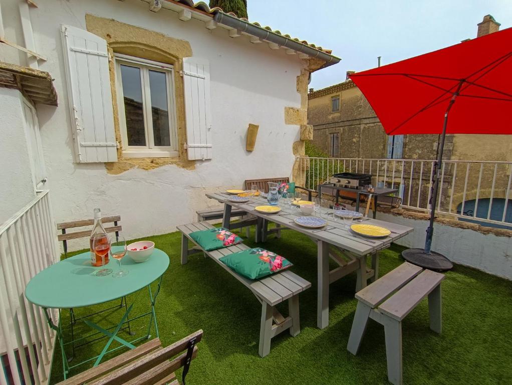 un patio avec une table, des chaises et un parasol rouge dans l'établissement Maison de Village 18ème Siècle Familiale 3 Chambres, à Mus
