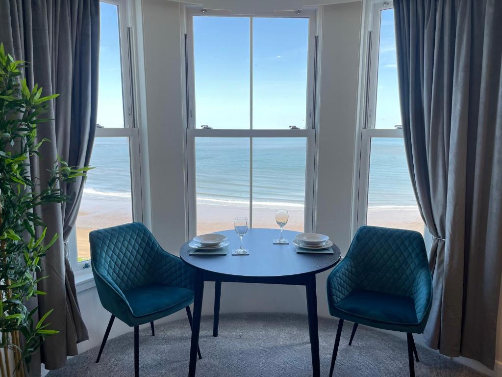 The Marlborough Sea View Holiday Apartments في سكرابورو: غرفة طعام مع طاولة وكرسيين ونافذة