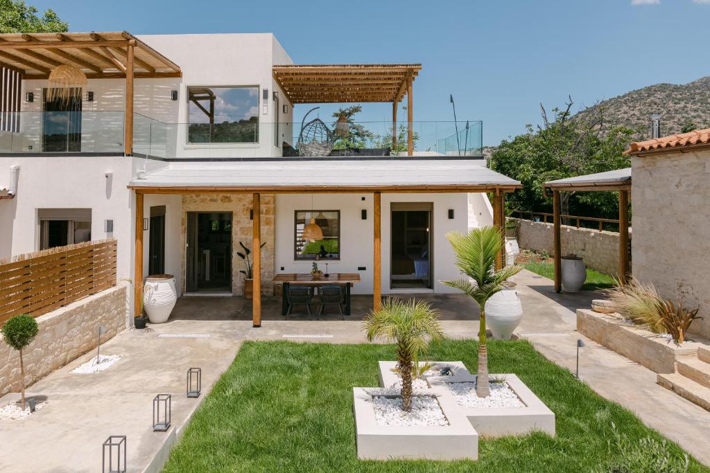 a house with a view of a courtyard with palm trees at Villa Aldea - Luxury Boho Style in Melidhónion