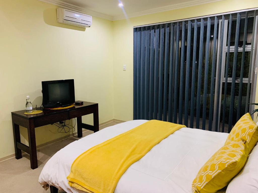 Schlafzimmer mit einem Bett, einem TV und einem Fenster in der Unterkunft Atonement private room in Matsapha