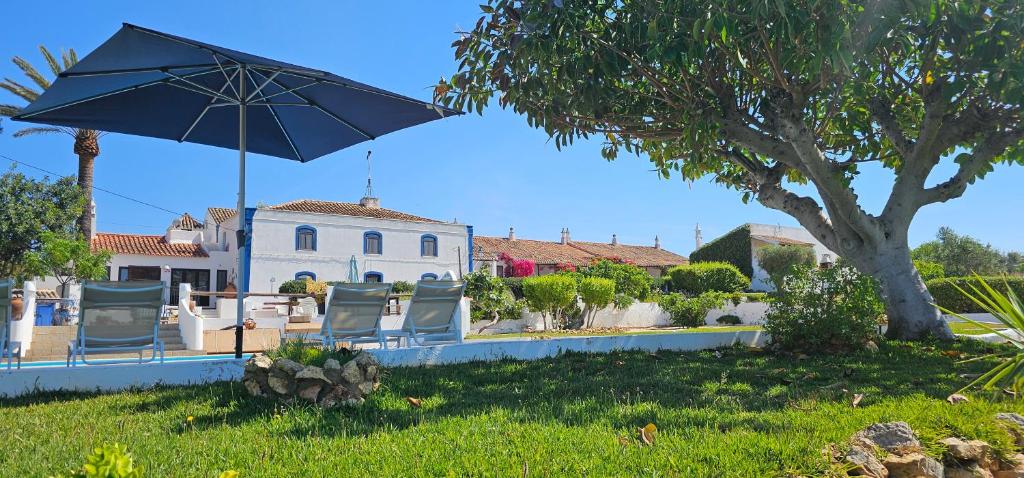 um par de cadeiras e um guarda-chuva no quintal em Quinta do Lagar - Rural Retreat by the Beach #10 em Albufeira