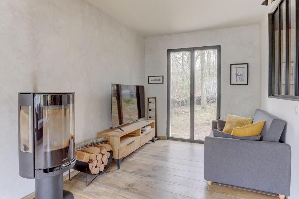ein Wohnzimmer mit einem Sofa und einem Stuhl in der Unterkunft Le Merisier - Guyancourt in Guyancourt