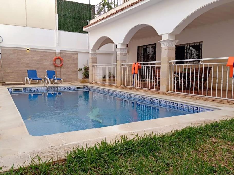 a swimming pool with two blue chairs and a building at Magnifique villa avec piscine 