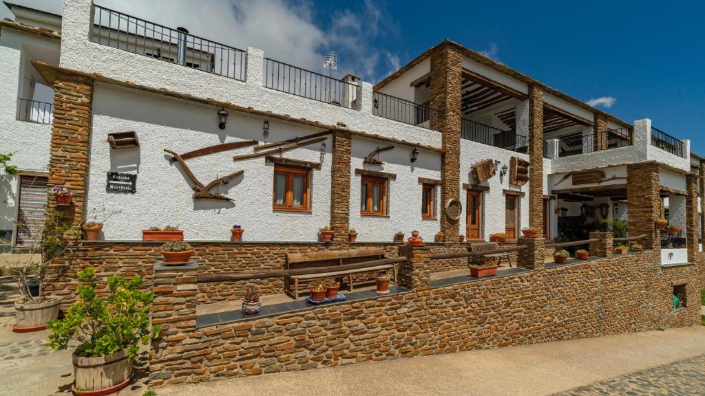 ein Gebäude mit einer Steinmauer mit Pflanzen darauf in der Unterkunft La Fragua II in Trevélez