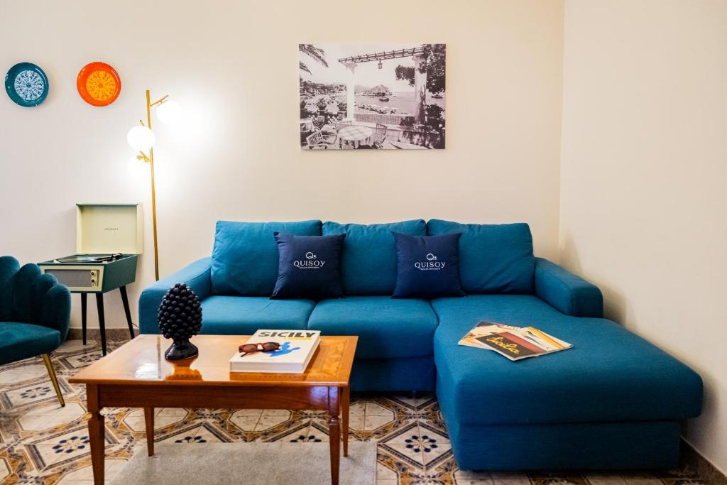 Sofá azul en la sala de estar con mesa en Achilles Apartment en Giardini Naxos