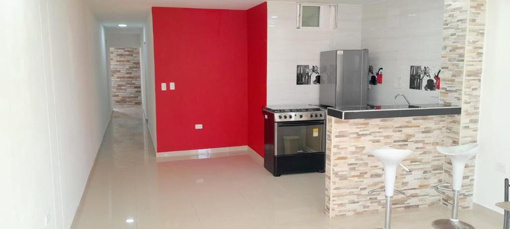 a kitchen with a stove and a red wall at apartahotel Cartagena in Cartagena de Indias