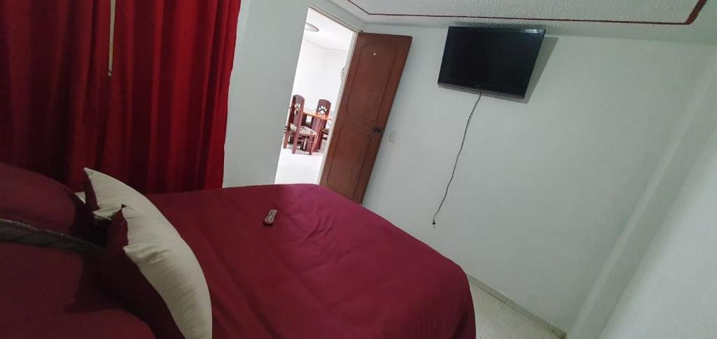 a bedroom with a red bed and a flat screen tv at VERDUN ROOMS in Bogotá