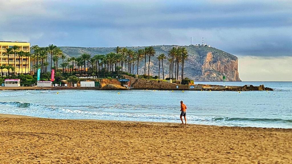 a person walking on a beach with a mountain in the background at Casa El Sueño in Jávea