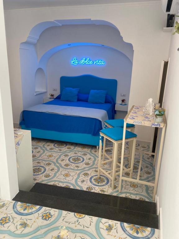Schlafzimmer mit einem blauen Bett und einem Tisch in der Unterkunft La Piccola Suite in Anacapri