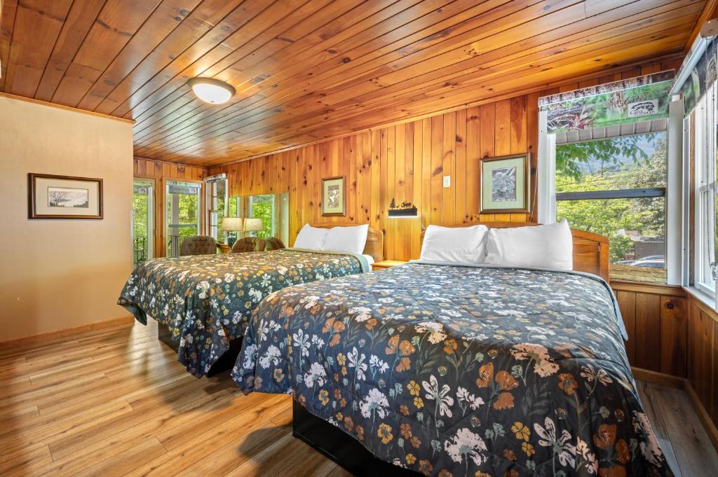 2 camas en una habitación con paredes de madera en Carr's Northside Hotel and Cottages en Gatlinburg