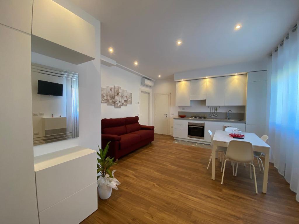 una cucina e un soggiorno con divano rosso e tavolo di Lellolocations - Casa Osina a San Costanzo