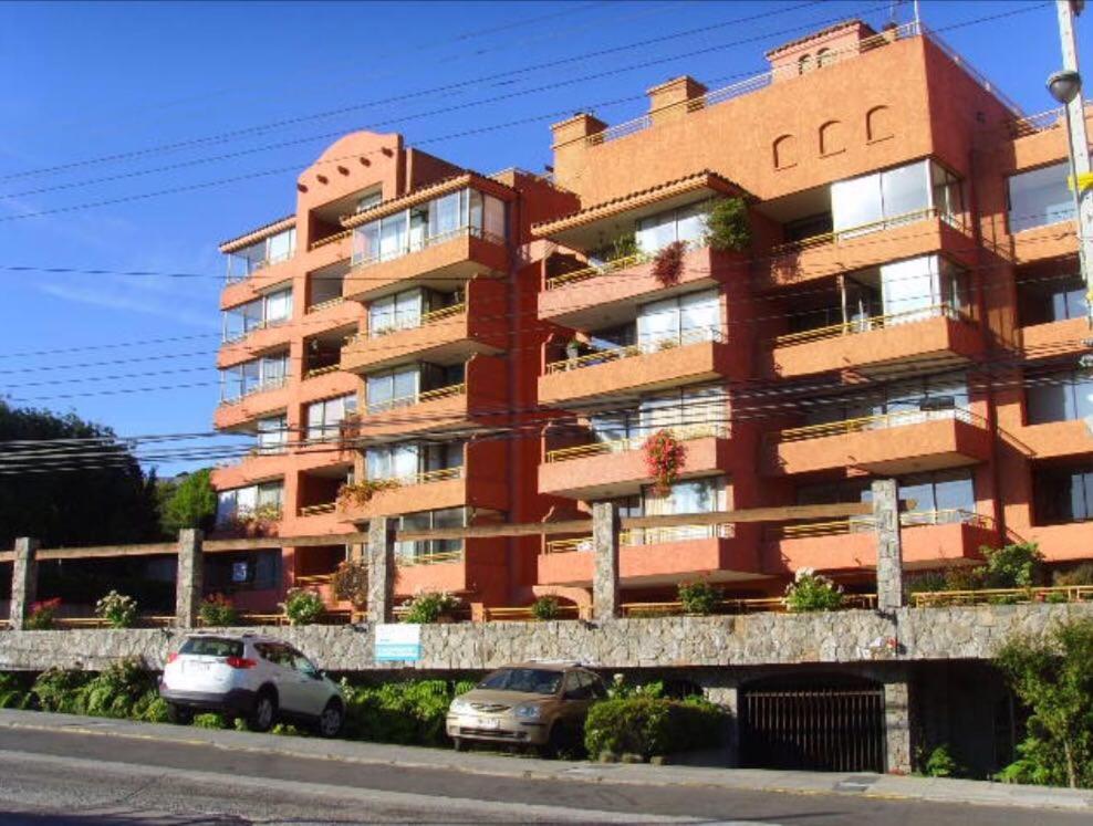 a red building with cars parked in front of it at Departamento en el corazón de Reñaca in Viña del Mar