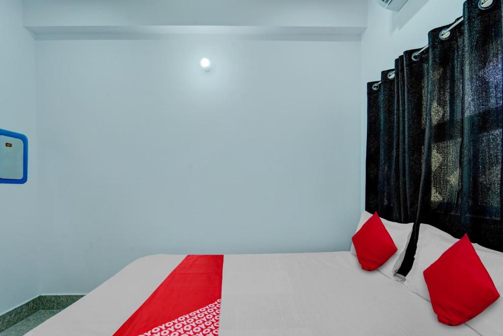 uma cama branca com almofadas vermelhas num quarto em OYO Flagship Your Room & Guest House em Patna