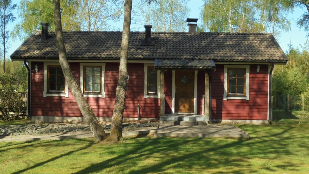 uma pequena casa vermelha com árvores em frente em Minnebo stuga em Hässleholm