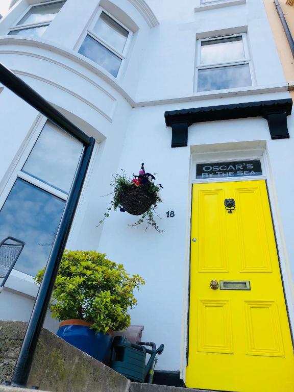 a yellow door on the side of a white house at Oscar's by the Sea in Bangor