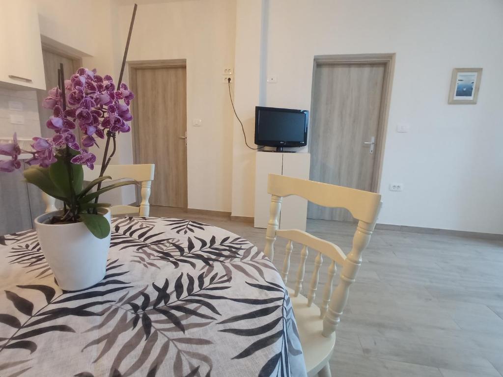 a room with a bed and a vase with purple flowers at Apartment Nada in Izola