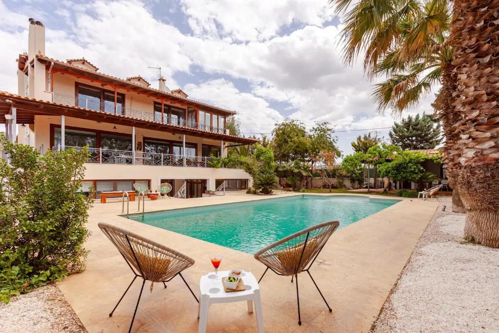 a villa with a swimming pool and two chairs at Riviera Paradiso in Aghia Marina