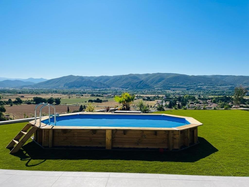 una gran piscina en un campo de césped con montañas en el fondo en Villa Contemporaine avec Vue Imprenable en Peyruis