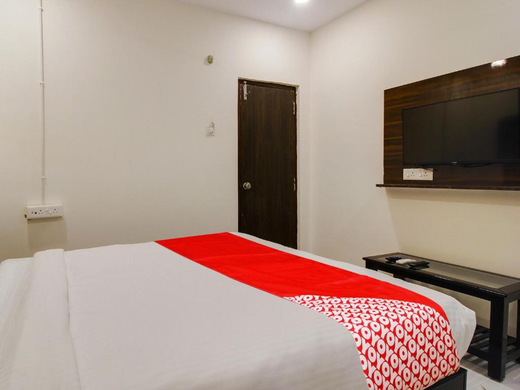 um quarto com uma cama e uma televisão de ecrã plano em Super OYO Sai Ganesh Residency em Warangal