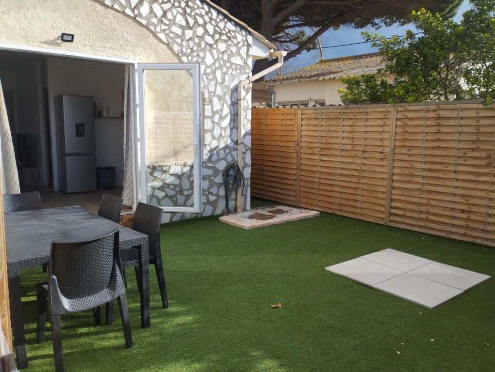 une cour arrière avec une table, des chaises et de l'herbe verte dans l'établissement Valras plage, sérignan maison à 400m de la plage, à Sérignan