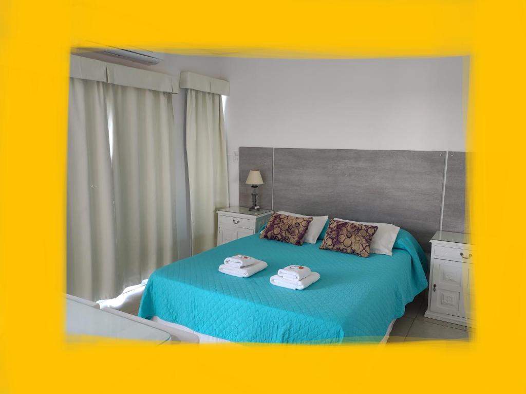 Un dormitorio con una cama azul con toallas. en Altos del Boulevard en Santiago del Estero