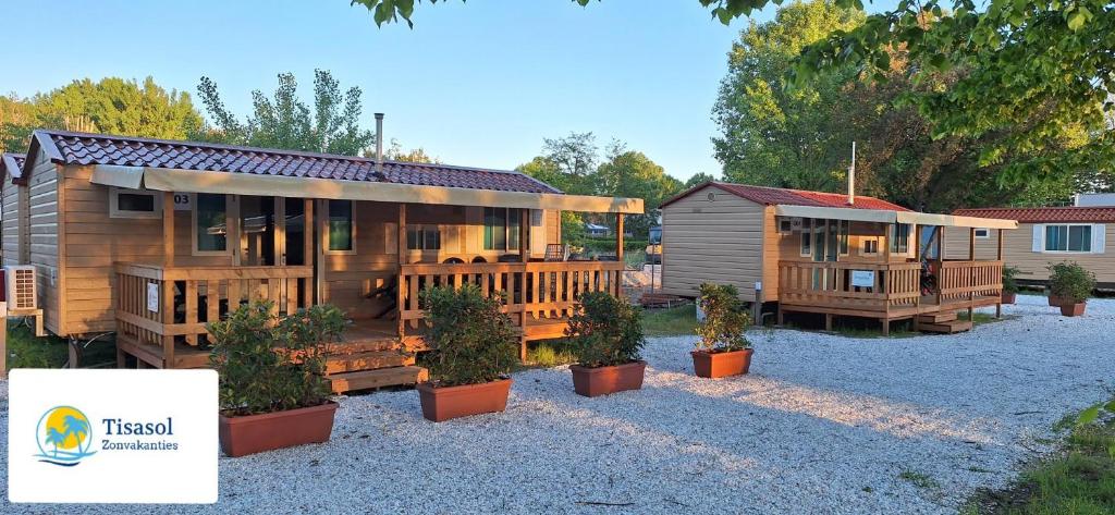 een groot houten huis met potplanten ervoor bij Mobile home Viareggio - Camping Paradiso- Including airco -Zona Gialla 016 in Viareggio