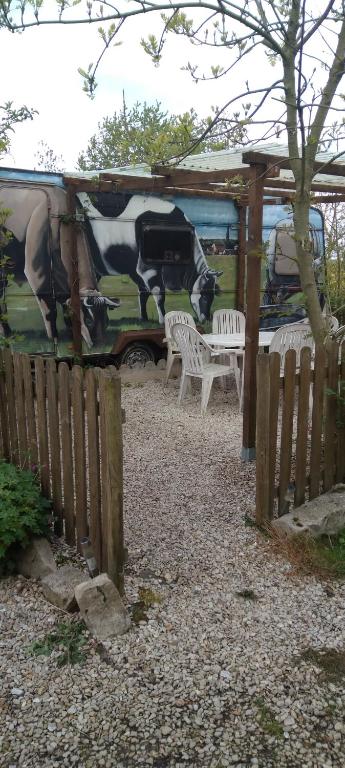 a fence with two white benches and a painting of cows at ferme pedagogique des pennetieres in Montcorbon