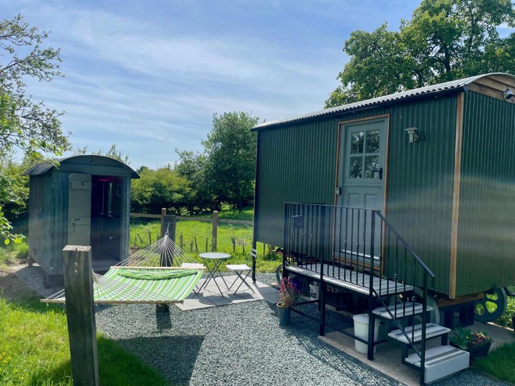 una casita verde con un banco y una mesa en The Orchard Retreat en Shrewsbury