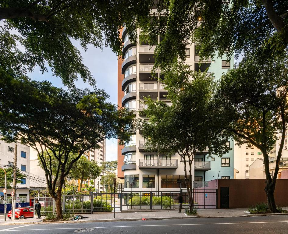 un edificio de apartamentos alto con árboles delante de él en Meu Club Haas en São Paulo