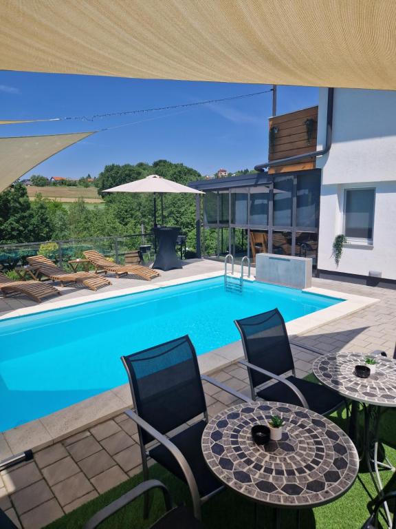 una piscina con 2 mesas y sillas junto a una casa en Aura Lux Holiday Home with Pool en Lopatinec