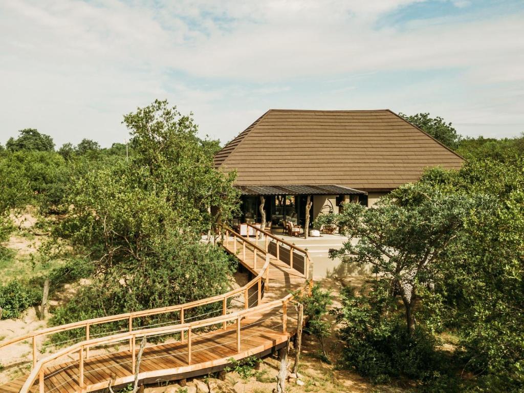 a building with a wooden walkway in front of trees at Maroelani Lodge- Greater Kruger Private Reserve in Hoedspruit