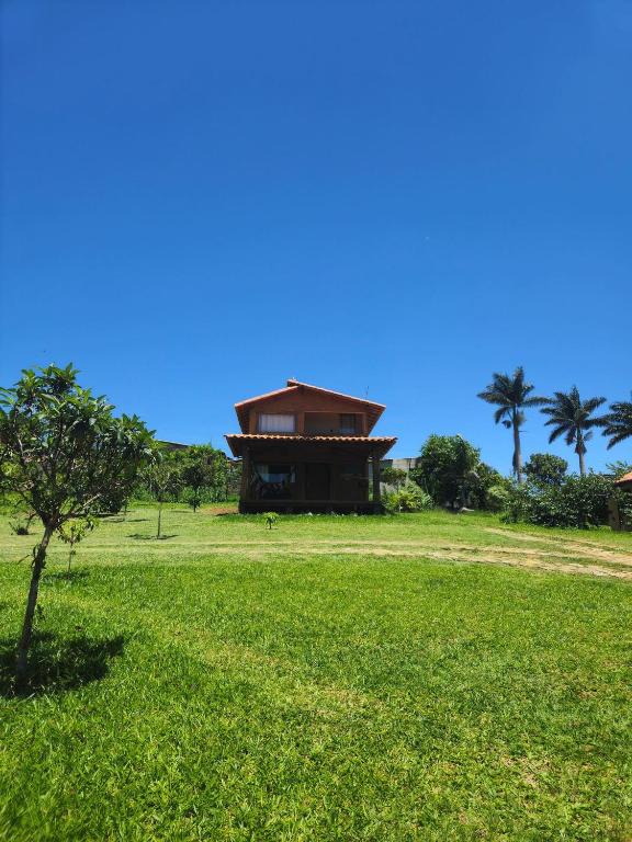 um edifício no meio de um campo com uma árvore em Chalés Vila Carrancas - Unidade Centro em Carrancas