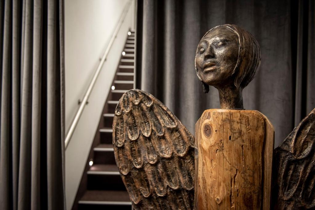une statue en bois d'un ange debout à côté d'un escalier dans l'établissement Hotel Šumava, à Železná Ruda