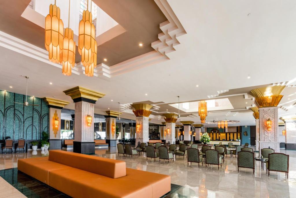 a lobby of a hotel with chairs and tables and chandeliers at Riu Vallarta - All Inclusive in Bucerías