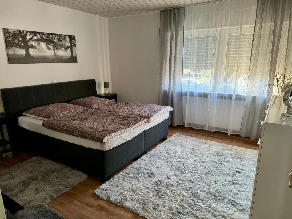 1 dormitorio con cama, ventana y alfombra en Kurstadt Apartment 2ZKB Balkon PKW Stlp-Self-Check-in en Bad Nauheim