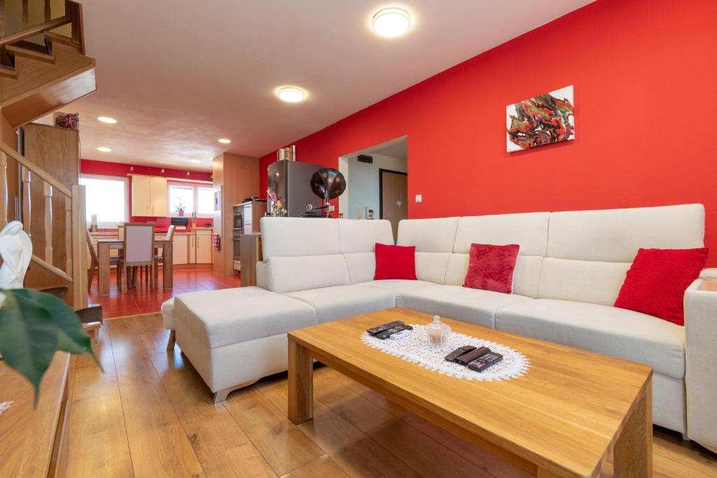 a living room with a white couch and red wall at Sherpa's Hostel High Tatras in Tatranska Strba