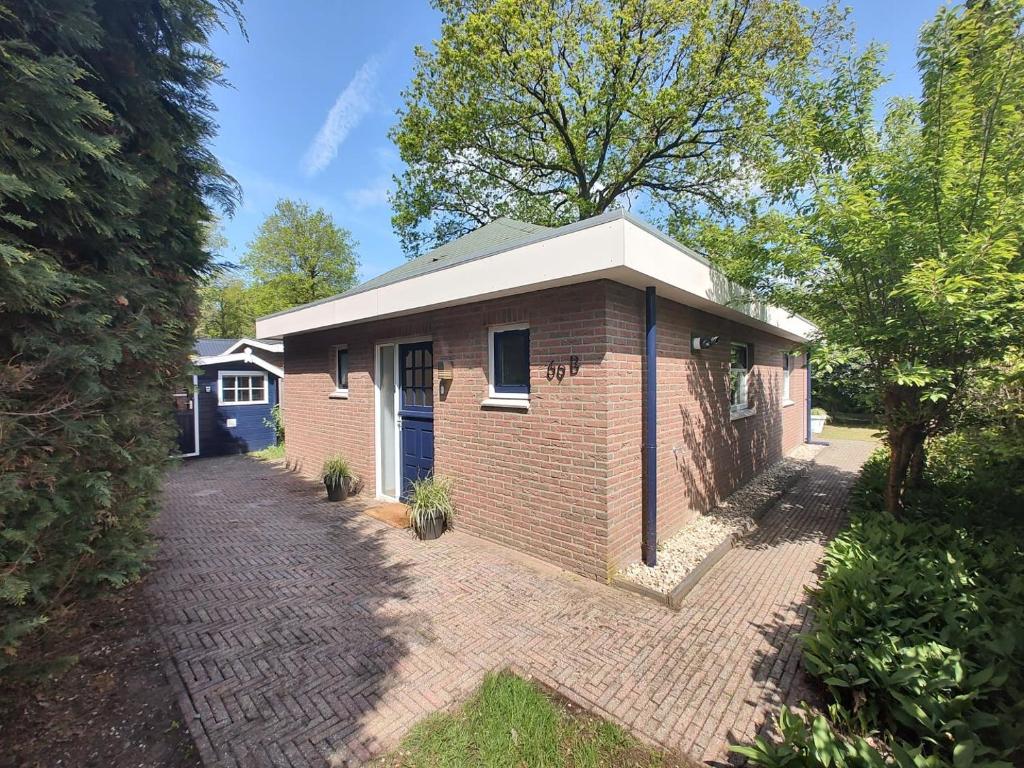 una pequeña casa de ladrillo en una entrada de ladrillo en Vakantiehuis op rustig bospark Veluwe en Voorthuizen