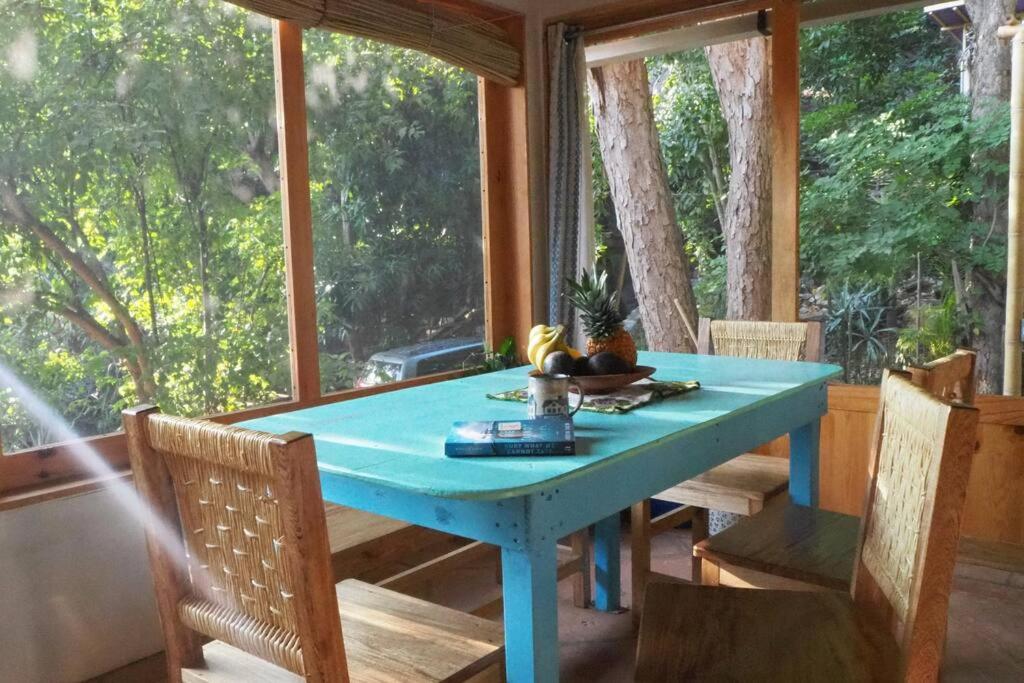 a blue table in a screened in porch with chairs at Charming Casa Pacifico with AC, Starlink and Great Location in Mazunte