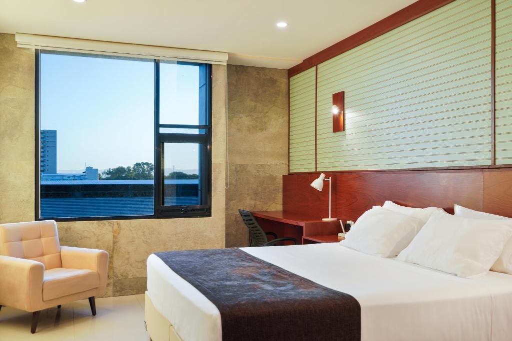 a hotel room with a bed and a chair and a window at Chairu Eco Hotel in Santa Cruz de la Sierra