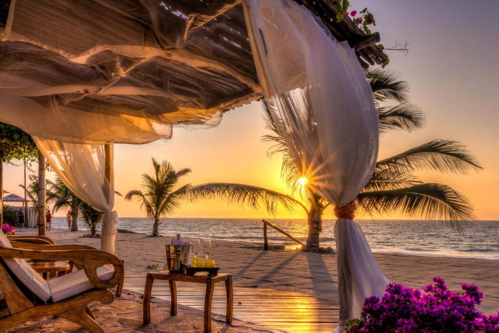 un tramonto sulla spiaggia con tavolo e sedie di Yemaya Boutique Hotel en Canoas a Canoas De Punta Sal