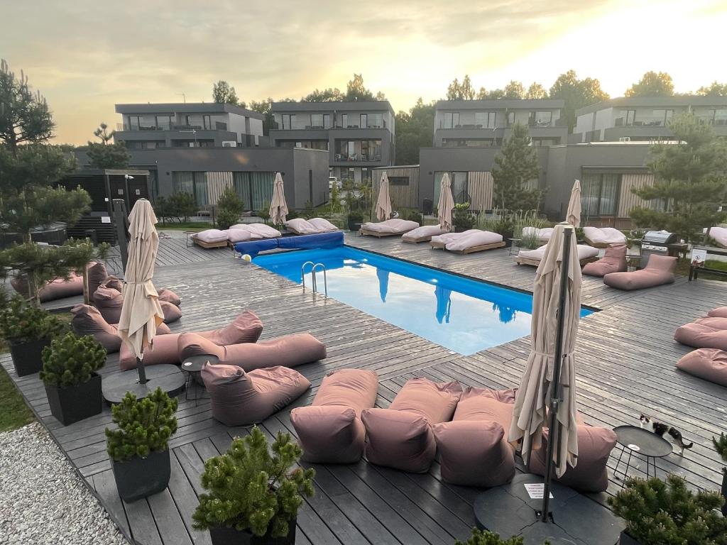 einen Pool mit rosa Kissen und Sonnenschirmen auf einer Terrasse in der Unterkunft Duneville Apartments Mano Jūra 2 in Palanga