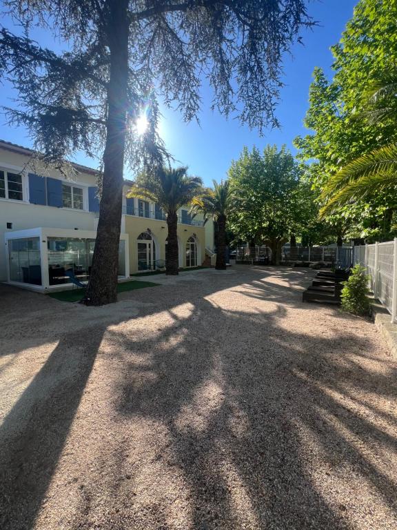 un bâtiment avec des arbres et des ombres au sol dans l'établissement Le refuge du littoral n1, à Grimaud